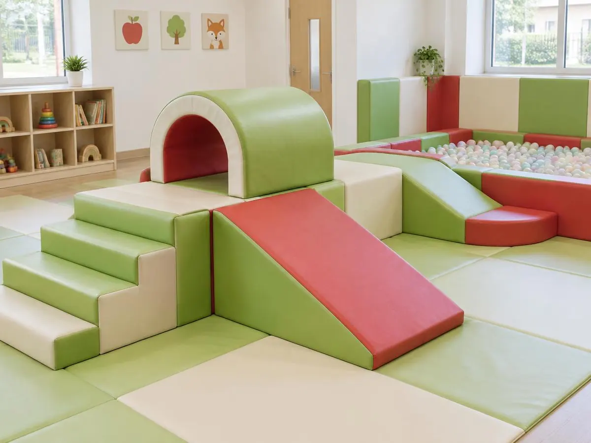 Indoor soft play area with padded green, cream and red steps, a slide, tunnel and ball pit
